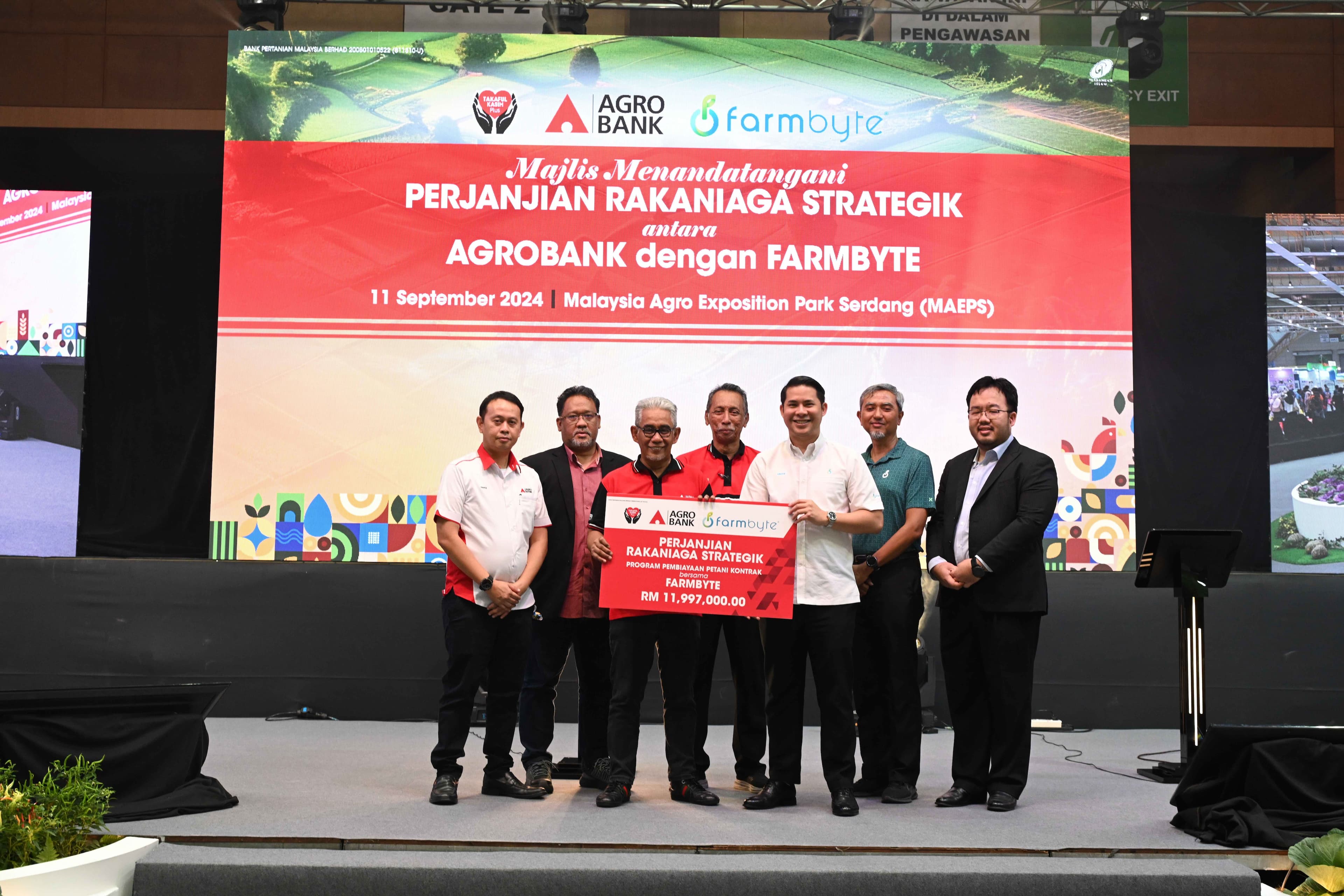FarmByte CEO, Syed Aiman (third from right), along with Agrobank President and CEO, Tengku Ahmad Badli Shah (third from left), holding the Contract Farming Financing Program plaque at the signing ceremony for the strategic business partner agreement at MA